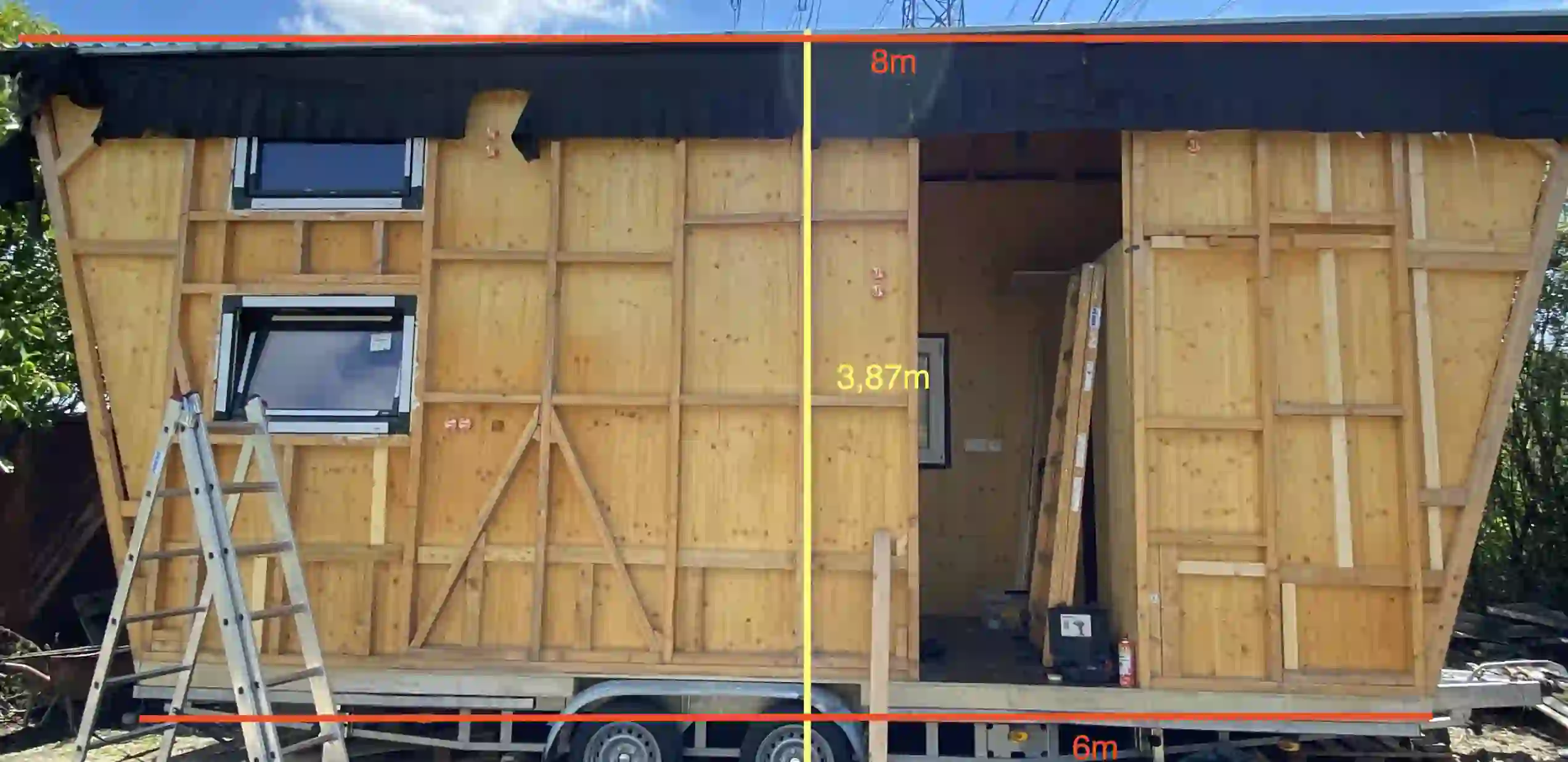 Das Tiny Haus mit geschlossenen Holzwänden, eingebauten Fenstern und eingezeichneten Maßen
